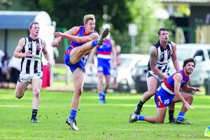 Castlemaine's Kal Huntly shrugs off a tackle from Gisborne's Thomas Wood. Photo: Peter Banko