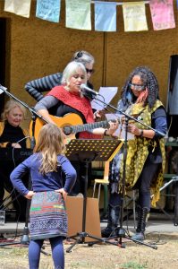 Young Minka Neale of Castlemaine looks on as local musicans Kavisha Mazzella and Trudy Edgeley take to the stage during Friday's International Women's Day celebration in the botanical gardens.